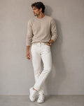 Hombre con jeans rectos color crudo de The Picks Club combinados con suéter beige y zapatillas blancas