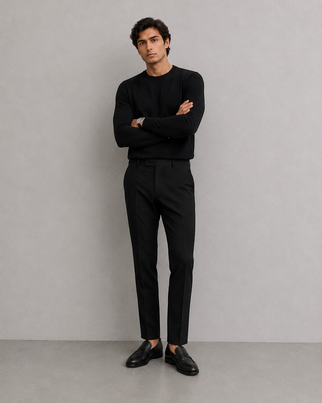Hombre con pantalones de vestir negros Mildnight Milano de The Picks Club, jersey negro y mocasines de cuero